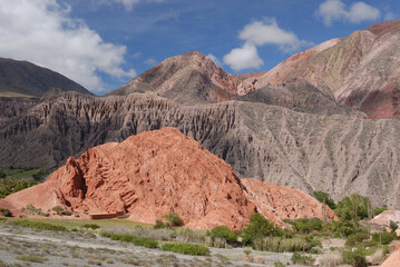 Altiplano. The arid desert and colorful mountains. View of the hiking path across the canyon. The orange sandstone and rocky formation part of Los Colorados in Purmamarca, Jujuy, Argentina.