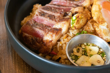 Wagyu beef with holy basil and chili fried rice served fried egg and fish sauce with Thai chilis. Top view on wooden table background.