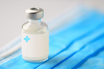 Medical vial of injectible medicine on a blue medical mask