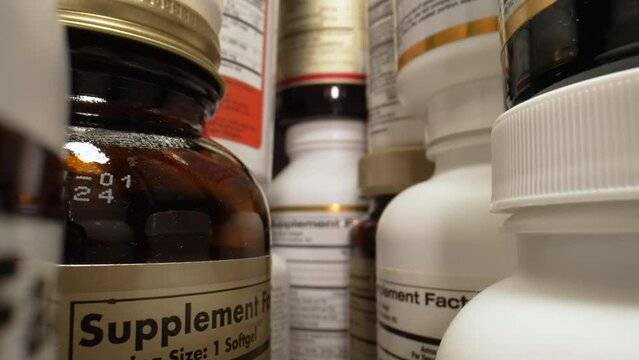 Plastic Cans for Tablets, Fish oil, Omega 3 or D-3 pills. The Camera Moves Through Many Containers of Dietary Supplements Pills for a Healthy Lifestyle. Pharmaceutical Industry