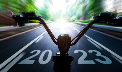 Abstract blur riding electric bicycle and new year number 2023 on road