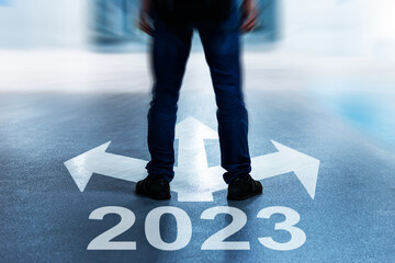 Man legs standing at three direction arrows and new year number 2023