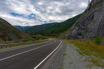 Naklejka premium A road surrounded by mountains in the Altai Republic. Gorny Altai