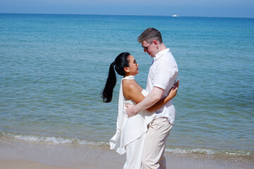 Male and female couple hugging at the beach bright blue sea.