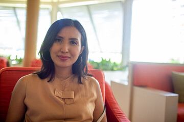 beautiful asian lady sitting on the sofa and smile at the camera