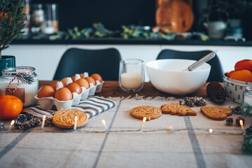 Ingredients for making Christmas cookies on the table against the backdrop of the kitchen. Plate with dough, milk, egg and New Year's decor