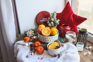 Beautiful Christmas still life. A cup of hot tea with a knitted sixth plaid on the windowsill with New Year's decor