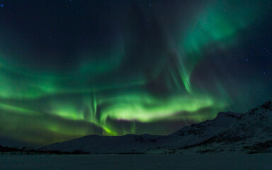 Northern lights over snowy mountains in norway