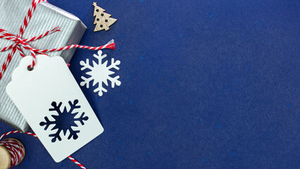 christmas present with gift tag and handmade decorations on dark blue background