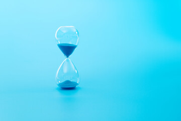 A hourglass on blue background - obrazy, fototapety, plakaty