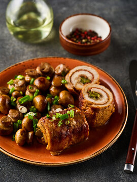 Pork roulade with pickles and bacon, served with fried mushrooms and green onions