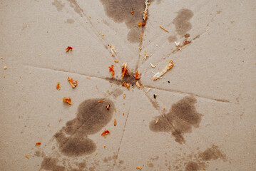 Eaten food, leftover crumbs and greasy marks on empty cardboard. Top view, close-up