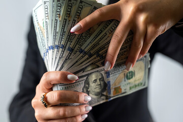 Beautiful young woman in a black jacket with dollar bills on a white background.