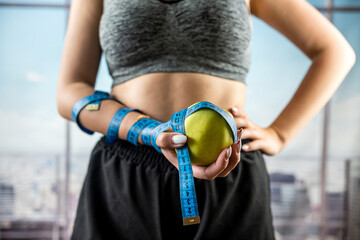 cropped portrait of fitness trainer with apple in hand and ribbon wrapped around arm. - Powered by Adobe