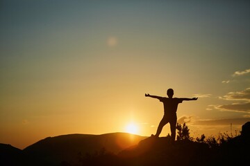 The silhouette of a man against the sunset in the mountains. Yellow colors of nature. The concept of travel