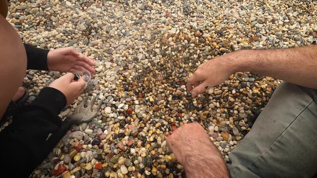 Man and child searching for rare and colourful rocks and pebbles. Slow motion. Close up.