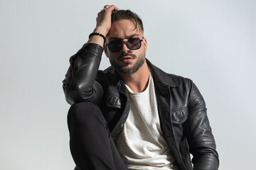 confident bearded man wearing cool leather jacket and sunglasses