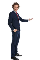 side view of elegant guy in suit with hand in pockets presenting to side