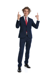 happy young guy in suit pointing fingers in the air and smiling