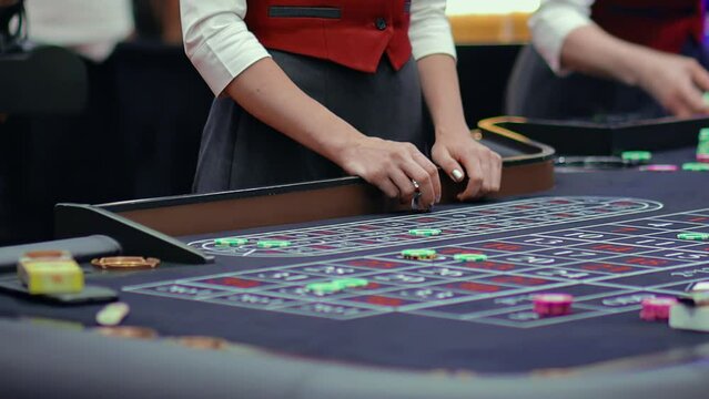 Roulette players place bets in casino, female dealer shows gesture with her hands about end of accepting bets. Fortune risk in Vegas chance. Gaming table. Gambling ludopathy. Lucky nightlife. Close up