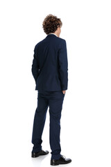 young man with long curly hair holding hands in pockets and posing