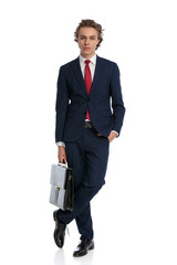 sexy young businessman holding bag and posing with hand in pocket