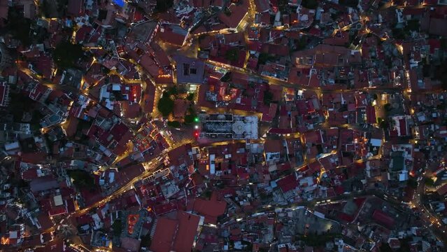 Aerial view above the illuminated church of Santa Prisca, in Taxco Guerrero, night in Mexico - cenital, drone shot