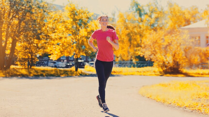 Fototapeta premium Happy smiling young woman doing sports running in the city park
