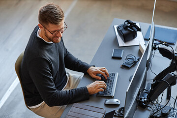 Top view at smiling software developer writing code while using computer and VR systems in office