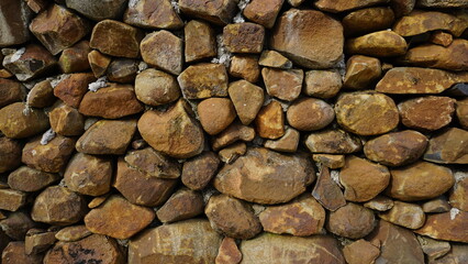 Beautiful background pattern image of a wall made of round stone red color rocks. Texture