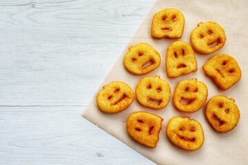Fried halloween potato shapes on parchment paper with white wood background.Creative art food idea for kids halloween party.Top view.Copy space