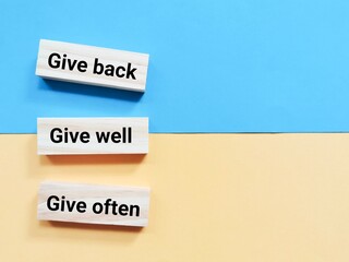 Quote give back give well and give often written on wooden blocks.
