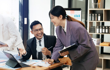Asian team business coworkers working on mobile laptop computer at office.Young woman holding tablet and pointing on touch screen. Horizontal, blurred background.Cropped.