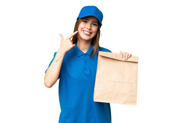 Young beautiful caucasian woman taking a bag of takeaway food over isolated background giving a thumbs up gesture