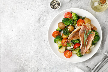 Dish with white baked fish with vegetables, perch with broccoli, cauliflower, tomatoes, potatoes on...