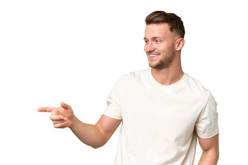 Young blonde caucasian man over isolated background pointing finger to the side and presenting a product