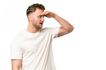 Young blonde caucasian man over isolated background with surprise expression while looking side