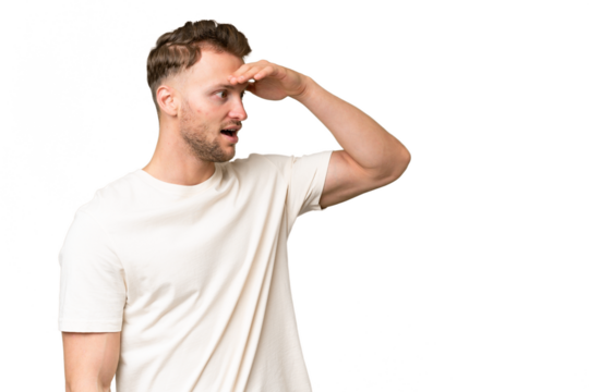 Young blonde caucasian man over isolated background with surprise expression while looking side