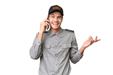 Young security man over isolated background keeping a conversation with the mobile phone with someone