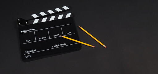 Fototapeta na wymiar Black clapper board or movie slate with 2 pencils isolated on black background.