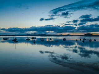 Aerial sunrise waterscape with boats, rain clouds and reflections