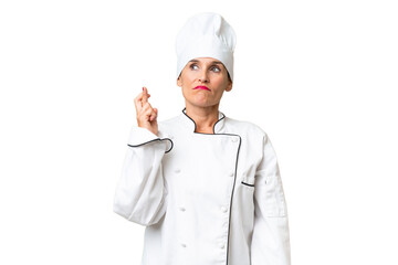 Middle-aged chef woman over isolated background with fingers crossing and wishing the best