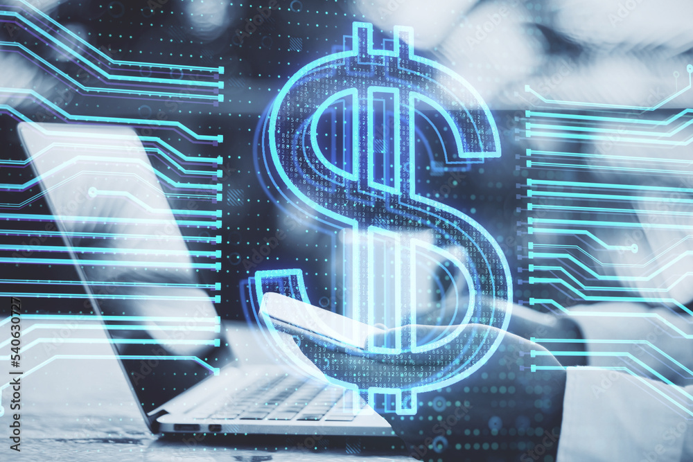 Poster close up of businessman hand using laptop keyboard and cellphone with glowing dollar hologram on blu