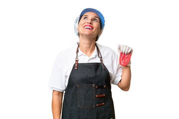 Butcher woman wearing an apron and serving fresh cut meat over isolated background laughing