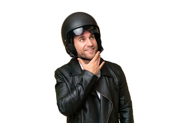 Young caucasian man with a motorcycle helmet isolated on green chroma background looking up while smiling
