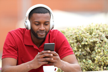Black man listening to music checking phone