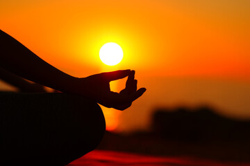 Yogi hand silhouette at sunset doing yoga