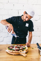 Italian chef pizzaiolo putting balsamic vinegar on pizza
