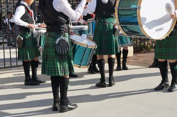 Green tartan kilts and black socks, flashes and brogues of a Highland Pipe Band drum core...