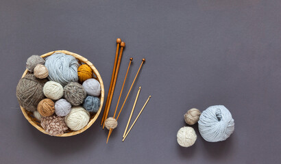 Top view on skeins and balls of wool yarn for hand knitting in wicker basket on gray background....